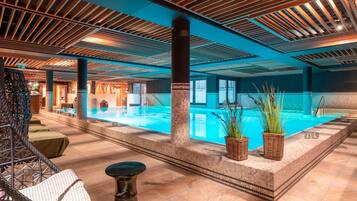 Een binnenzwembad, ligstoelen bij het zwembad