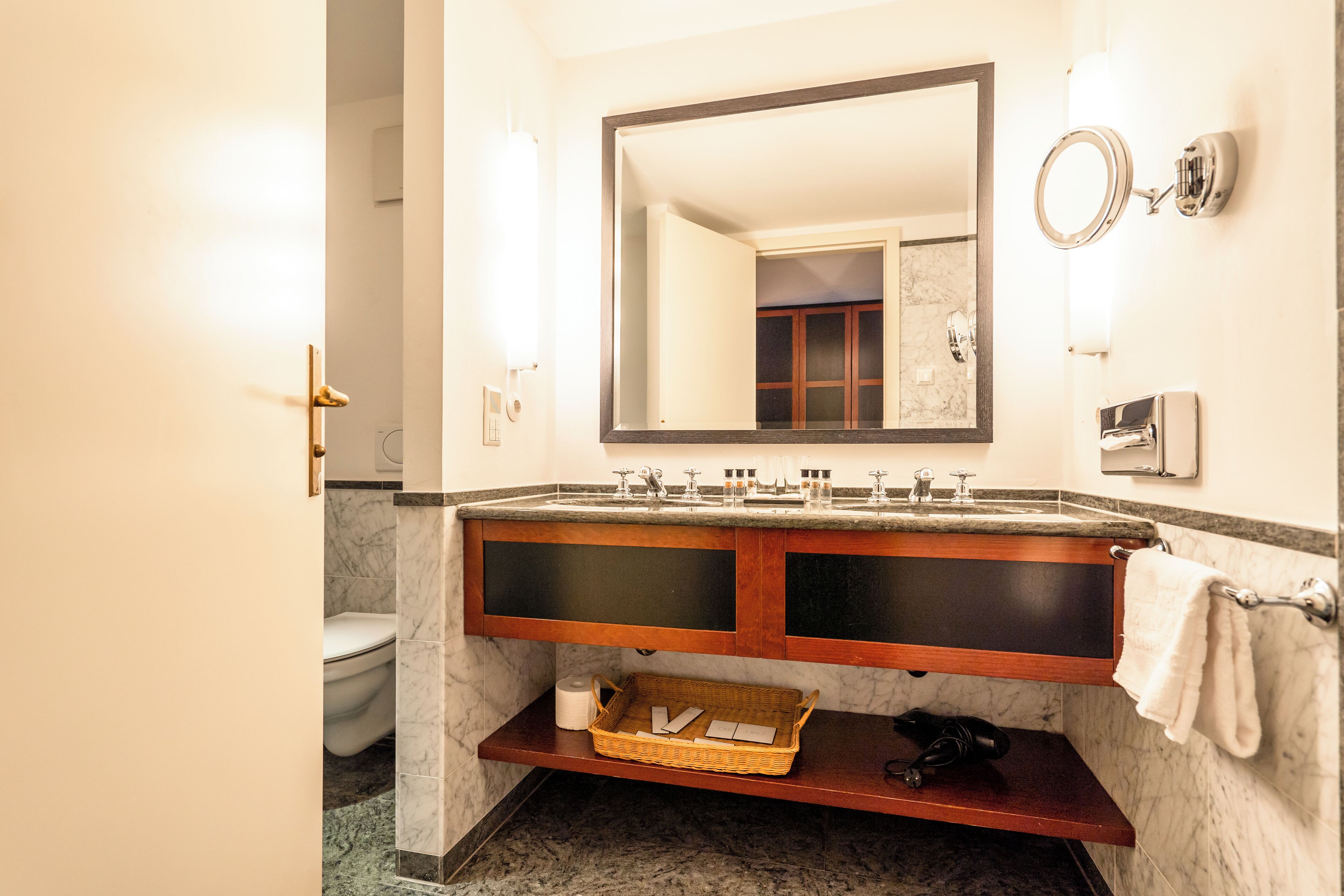 A bathroom with a marble sink, a large mirror, and a towel rack.