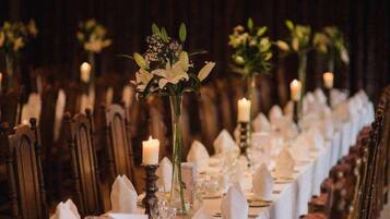 A long table set for a formal event with candles and floral centerpieces.