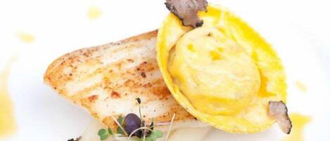 A dish with a piece of fish and a yellow sauce.
