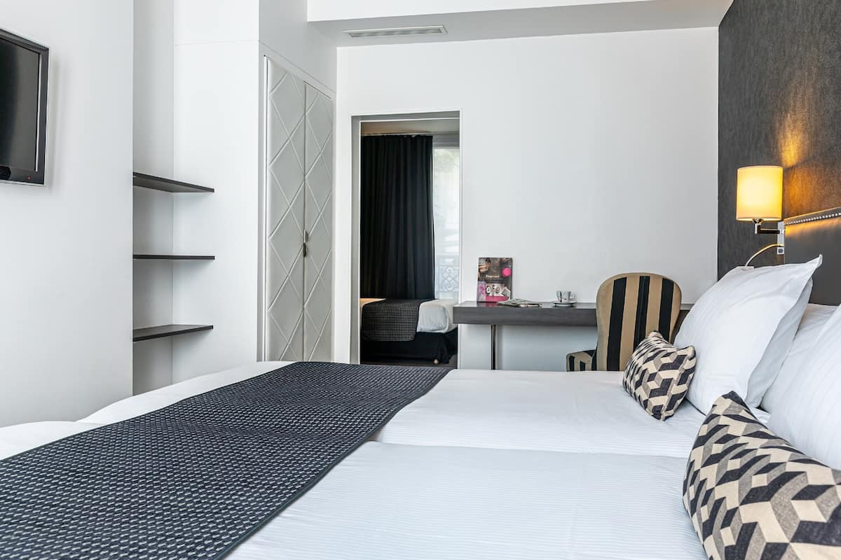 Een hotelkamer met een groot bed, een bureau, een stoel en een aan de muur bevestigde televisie.