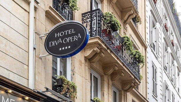 Un edificio con un letrero que dice "HOTEL DIVA OPERA" y una barbería con un letrero "ME".