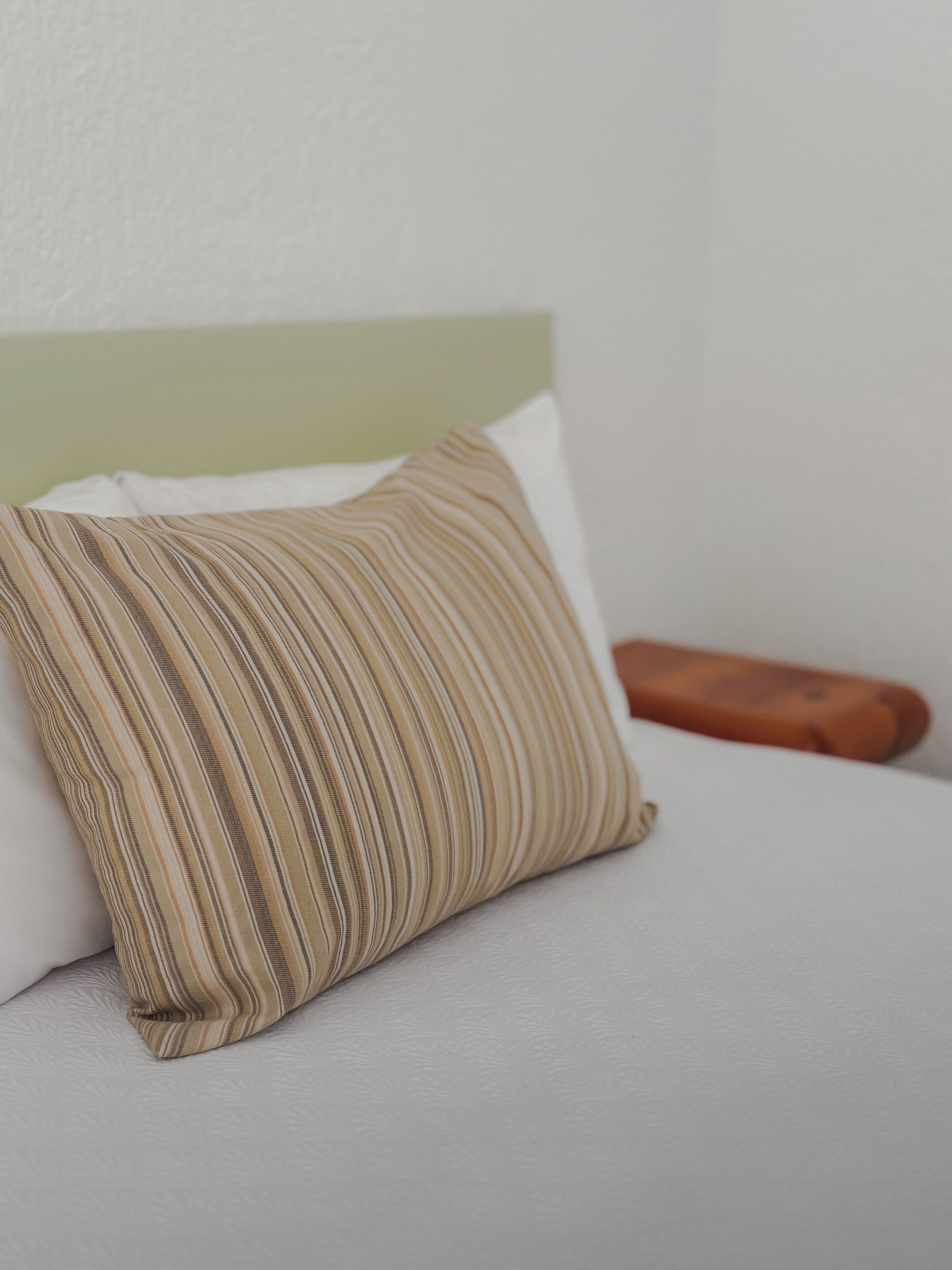 A pillow with a striped pattern on a bed.