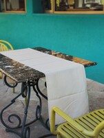 Una mesa con mantel blanco, una silla amarilla y una pared color aguamarina.