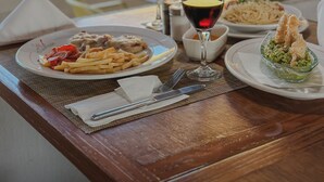 Una mesa con platos de comida, una copa de vino tinto y una copa de vino blanco.
