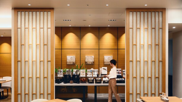 A restaurant with wooden panel dividers, tables, chairs, and a counter with kitchen appliances. - Hotel JAL City Miyazaki (Miyazaki)