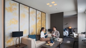 A modern hotel room with a sofa, a coffee table, a desk, and a large abstract wall art piece. - Hotel JAL City Miyazaki (Miyazaki)