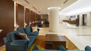 A modern lobby with a reception desk, blue sofas, and a large pillar. - Hotel JAL City Miyazaki (Miyazaki)