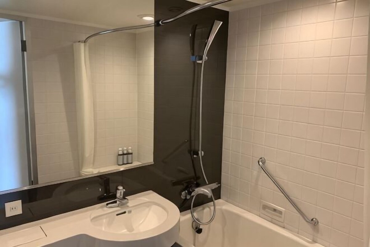 A modern bathroom with a white sink, mirror, and bathtub.