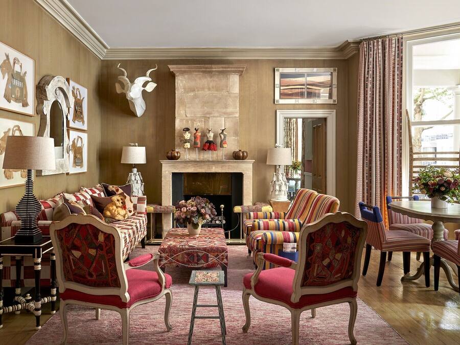 A traditional living room with a fireplace, patterned furniture, and artwork on the walls.
