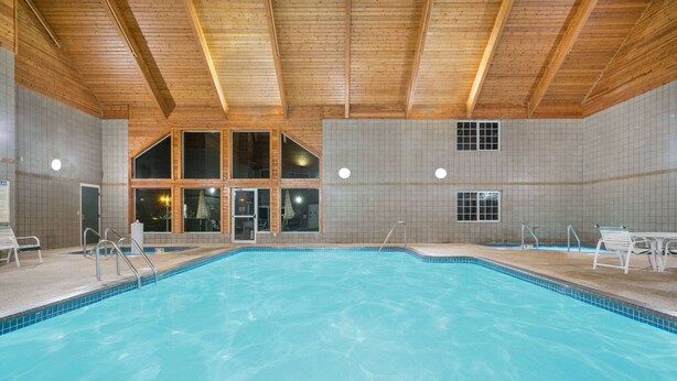Una piscina interior con vigas de madera, paredes con azulejos y vistas claras al área de la piscina.