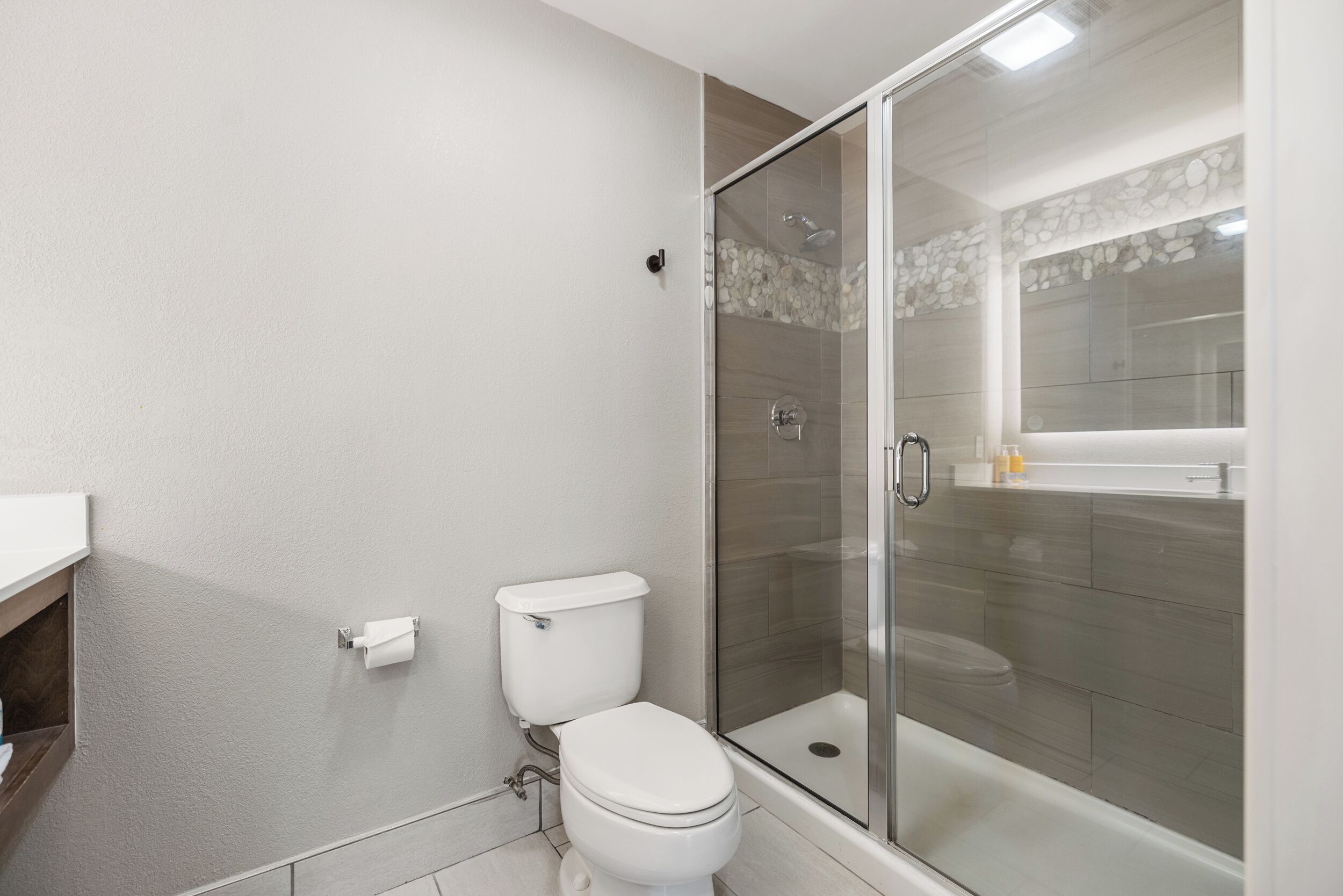 Ein Badezimmer mit Toilette, einer gläsernen Dusche und einem weißen Waschbecken.