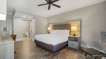 A modern bedroom with a large bed, wooden headboard, bedside lamps, and a ceiling fan.