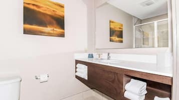 A modern bathroom with a white sink, wooden vanity, and a large mirror.