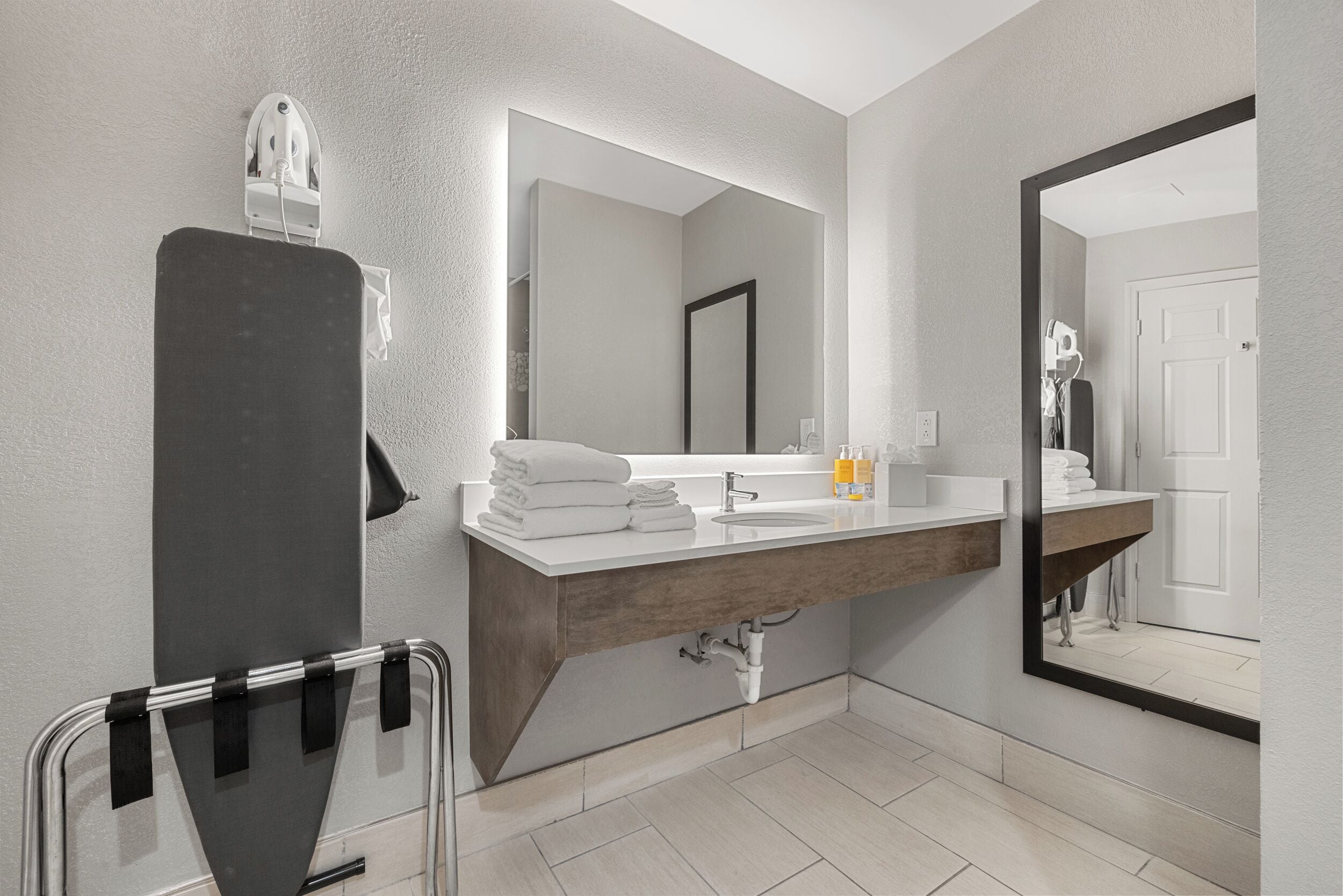A modern bathroom with a large mirror, a sink, and a towel rack.
