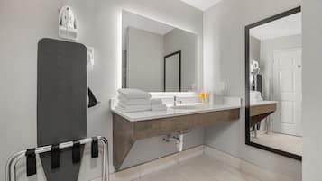 Un baño moderno con un espejo grande, un lavamanos y un perchero para toallas.