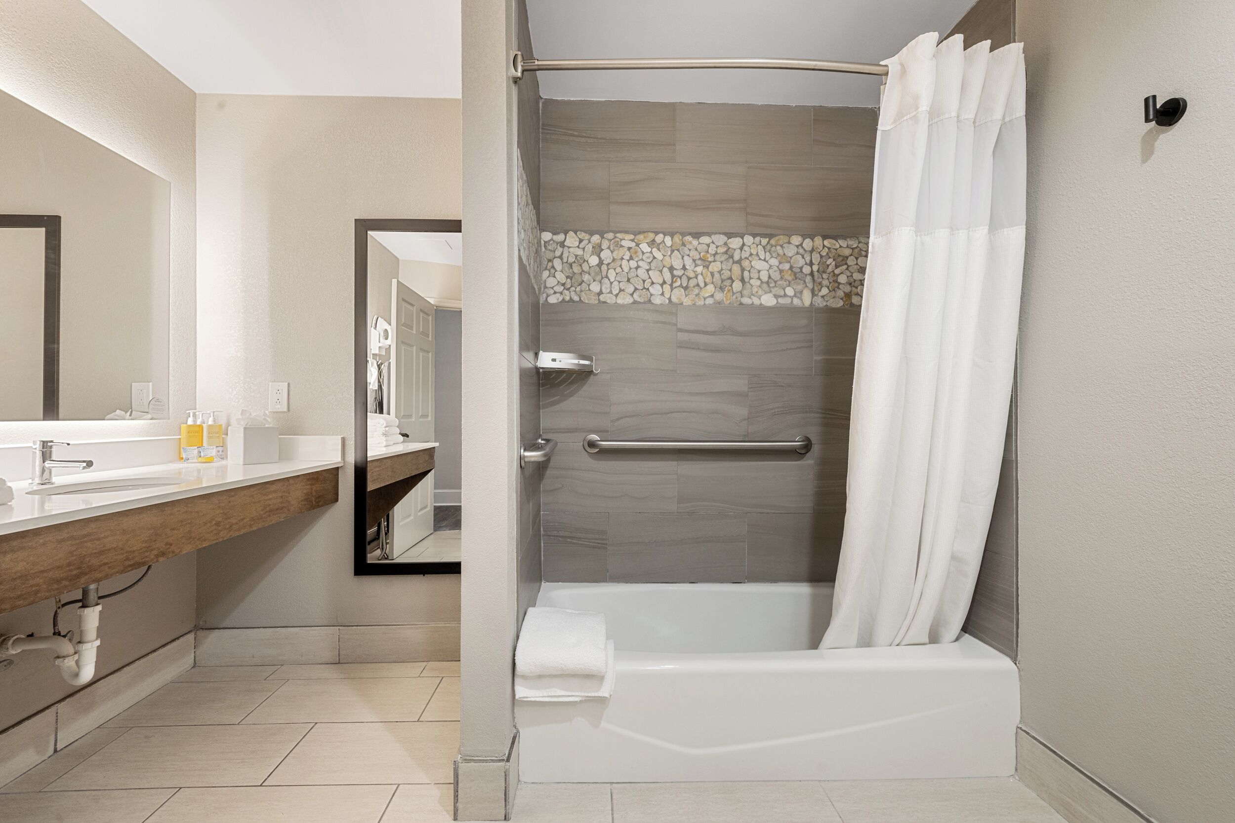 A modern bathroom with a bathtub, a shower, and a vanity with a mirror.