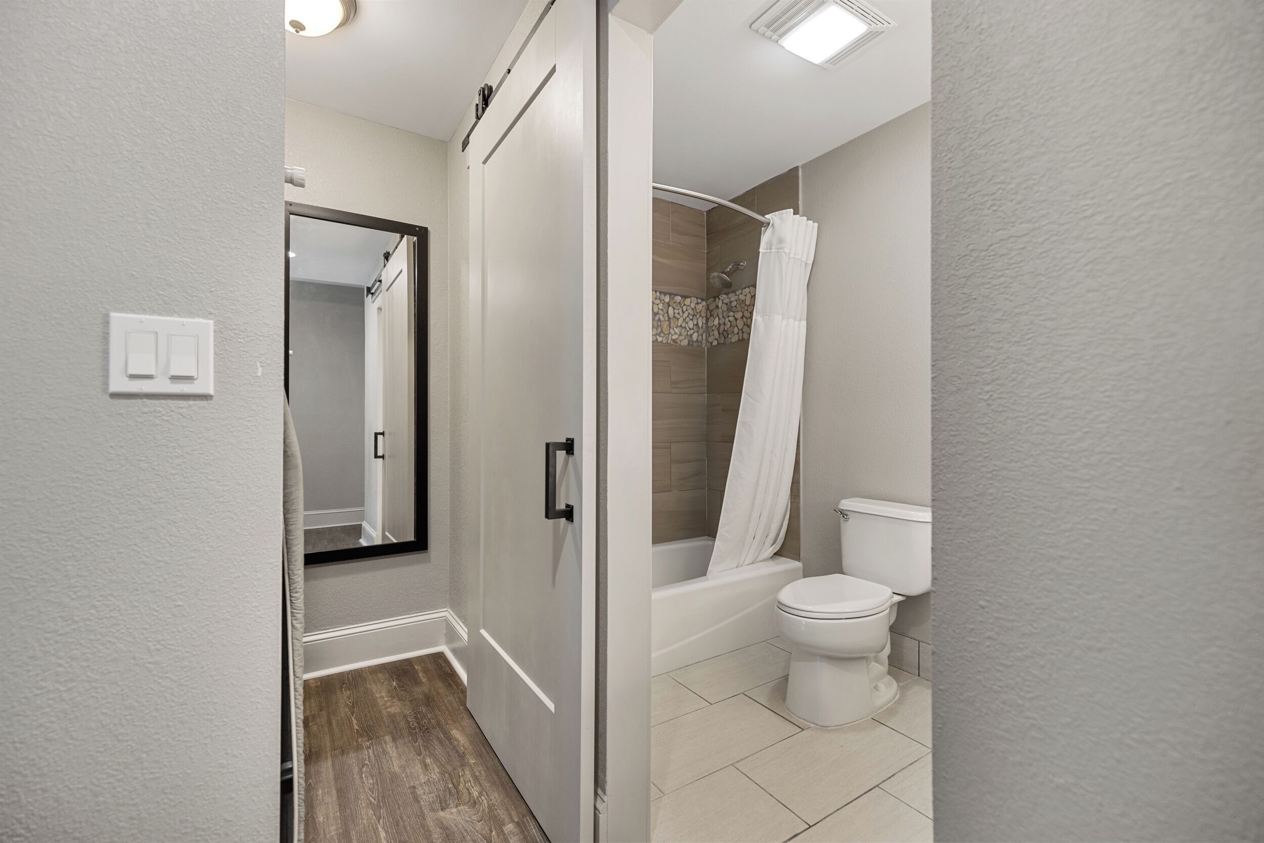 A modern bathroom with a shower, toilet, and a mirror.