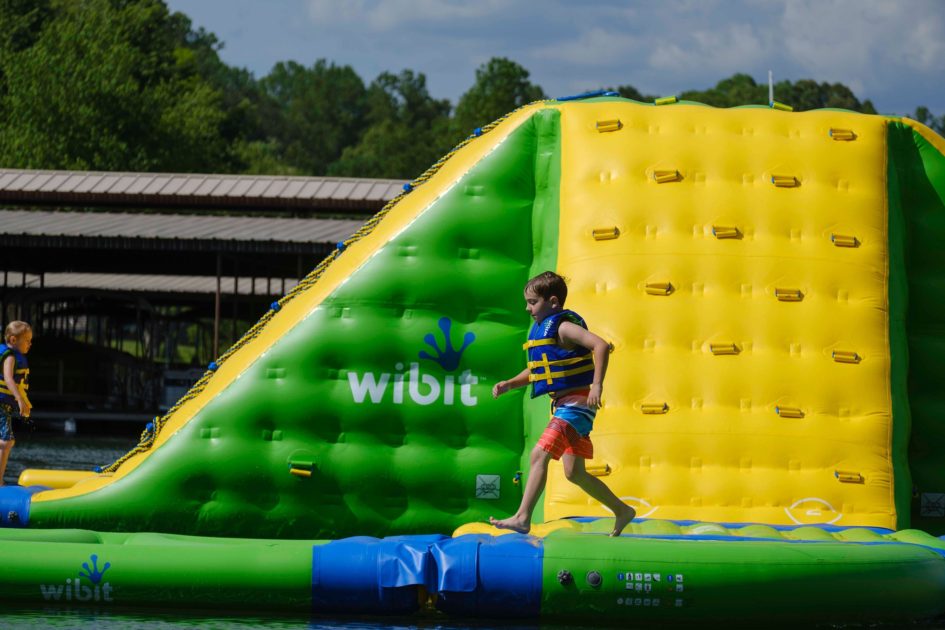 Un tobogán acuático inflable grande con diseño verde y amarillo, que presenta el nombre de la marca 'wibit'.