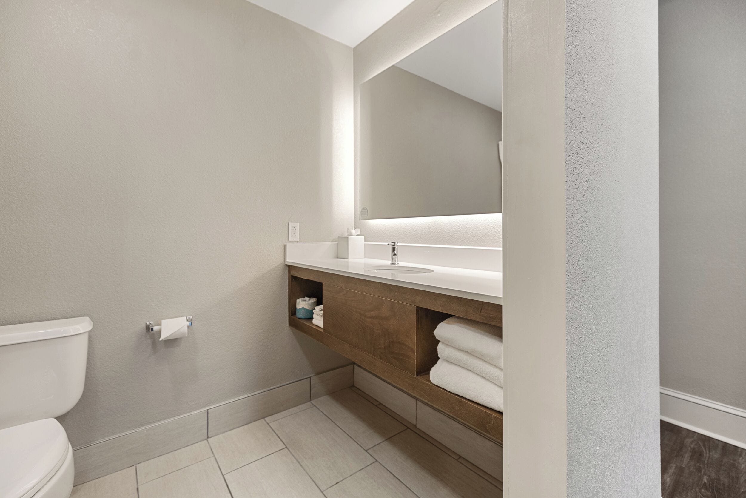 Een moderne badkamer met toilet, wastafel en spiegel.
