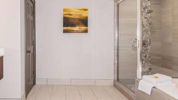 Un baño con ducha de vidrio, una puerta y un cuadro en la pared.