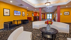 A lobby with a curved white seating area, a round table with a vase of flowers, and framed pictures on the walls. - Best Western The Inn At The Fairgrounds (Syracuse)