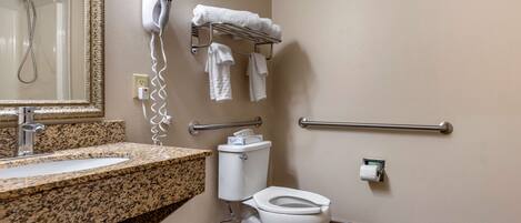 A bathroom with a granite countertop sink, a toilet, a hand dryer, and a towel rack.