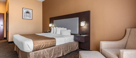 Una habitación de hotel con una cama grande, mesitas de noche, una silla y un cuadro enmarcado en la pared.