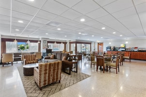 A spacious lobby with seating areas, a reception desk, and a visible kitchen area.