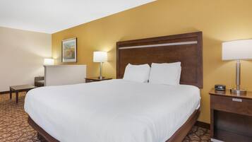 A hotel room with a large bed, two bedside tables with lamps, a small desk, and a framed picture on the wall.