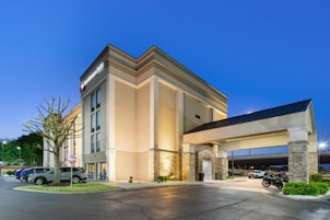 A hotel entrance with a covered parking area, a sign indicating 'Do Not Enter' on the street, and a motorcycle parked outside.