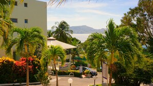 A resort with a pool, palm trees, and a view of the ocean. - Karibea Squash Hôtel (Fort-de-France)