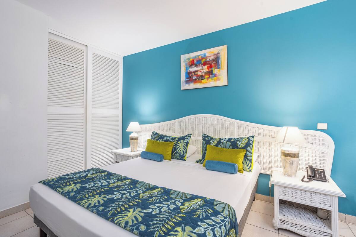 A bedroom with a bed, a nightstand, a lamp, and a wall art piece.