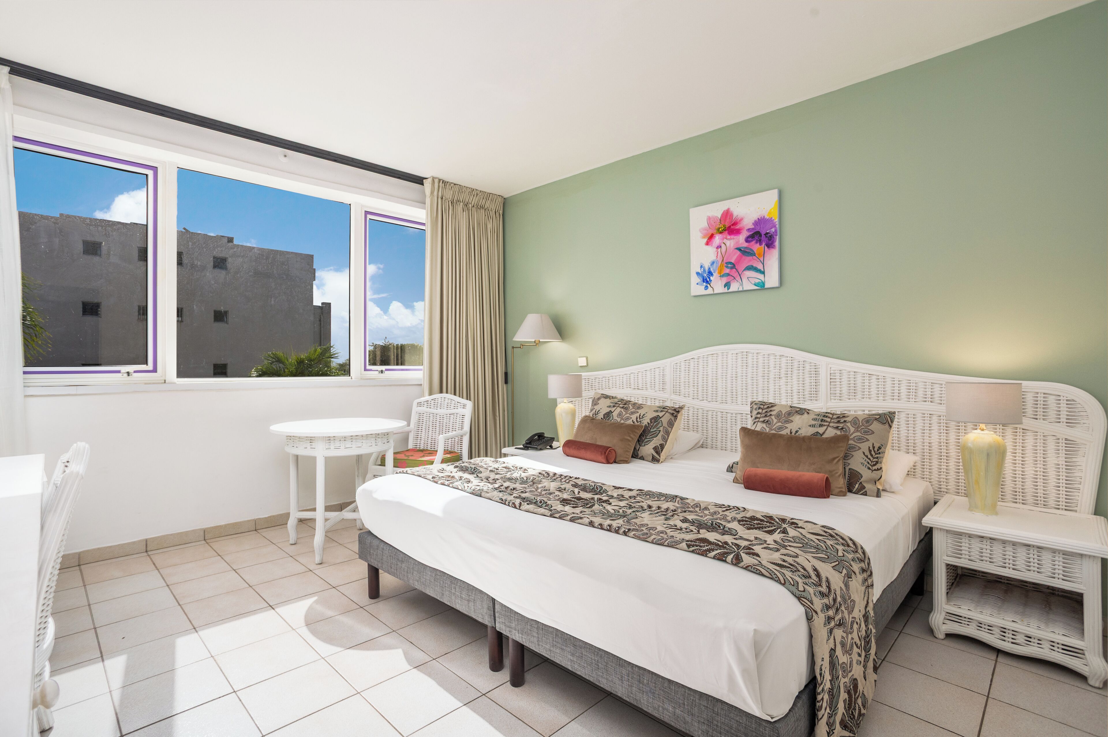 A bedroom with a bed, bedside tables, a chair, and a window with a view of buildings.