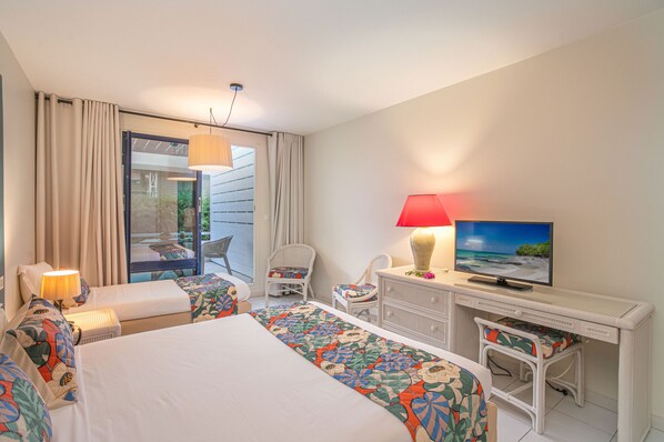 Habitación de hotel con dos camas, televisión, escritorio y vistas al exterior.