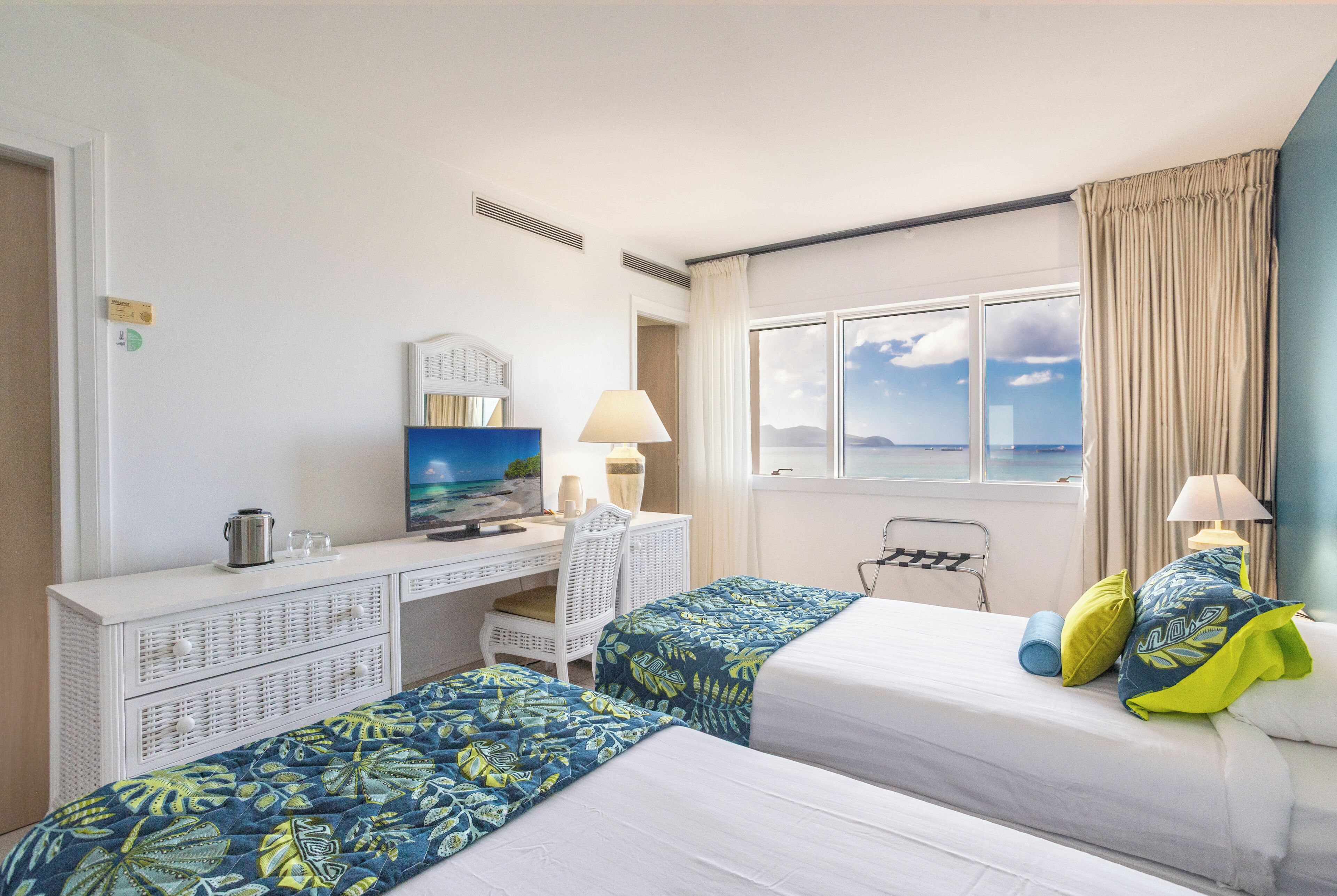 Une chambre d’hôtel avec deux lits, un bureau, une chaise, une télévision et une fenêtre donnant sur un beau paysage.