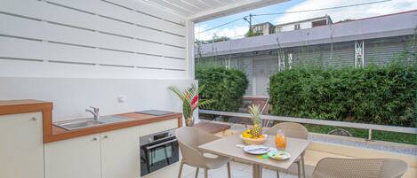 A balcony with a kitchen area, including a sink, stove, and chairs.