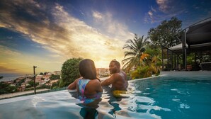 A couple in a swimming pool with a sunset view. - Karibea Squash Hôtel (Fort-de-France)