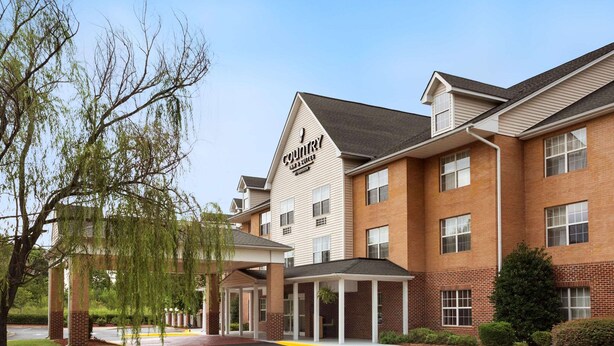 A Country Inn & Suites hotel with a brick facade, covered parking, and a clear sky.