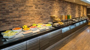 A buffet with various food items and beverages, set against a brick wall. - Real Inn Perinorte (Tlalnepantla de Baz)