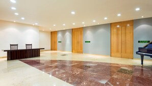 A spacious lobby with a grand piano, a reception desk, and wooden doors. - Real Inn Perinorte (Tlalnepantla de Baz)
