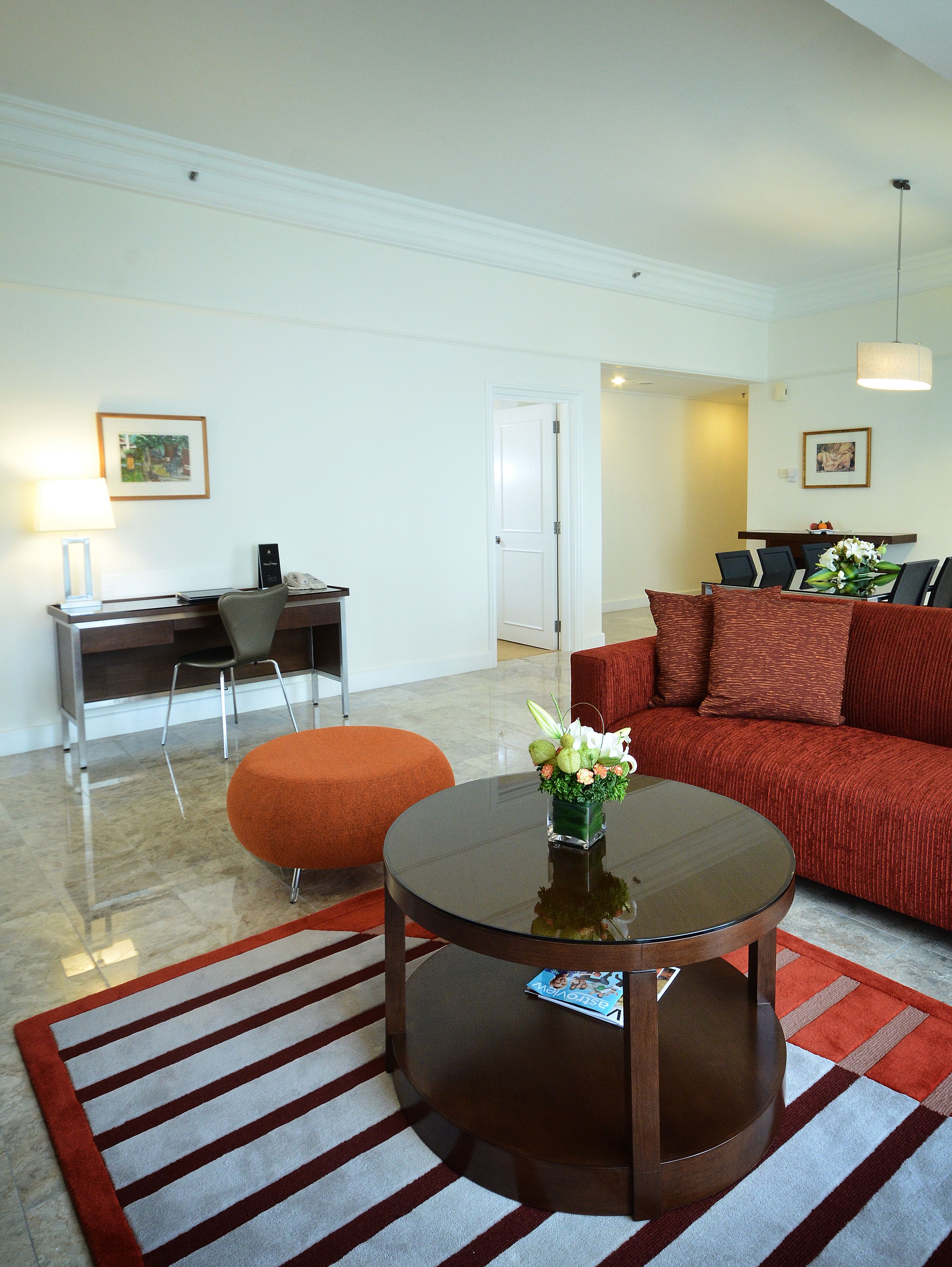 A modern living room with a round coffee table, a red sofa, and a striped rug.