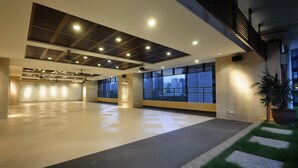 Un espacio interior amplio con techo alto, iluminación empotrada y grandes ventanales que ofrecen vistas a la ciudad.