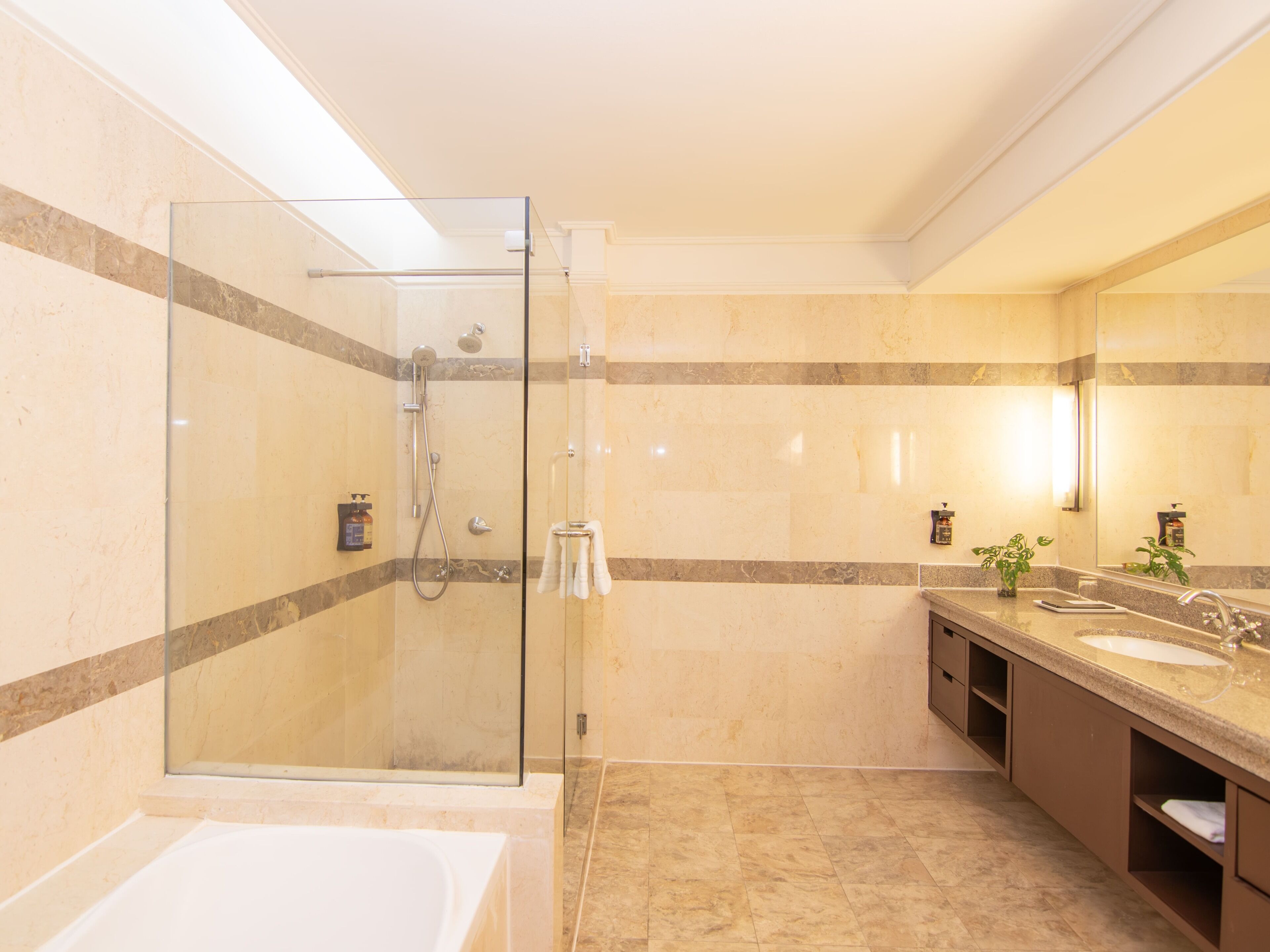 A modern bathroom with a glass-enclosed shower, a bathtub, and a vanity with a mirror.