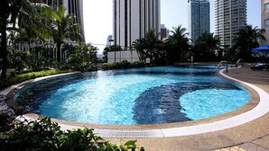 Una piscina rodeada de follaje y edificios altos.