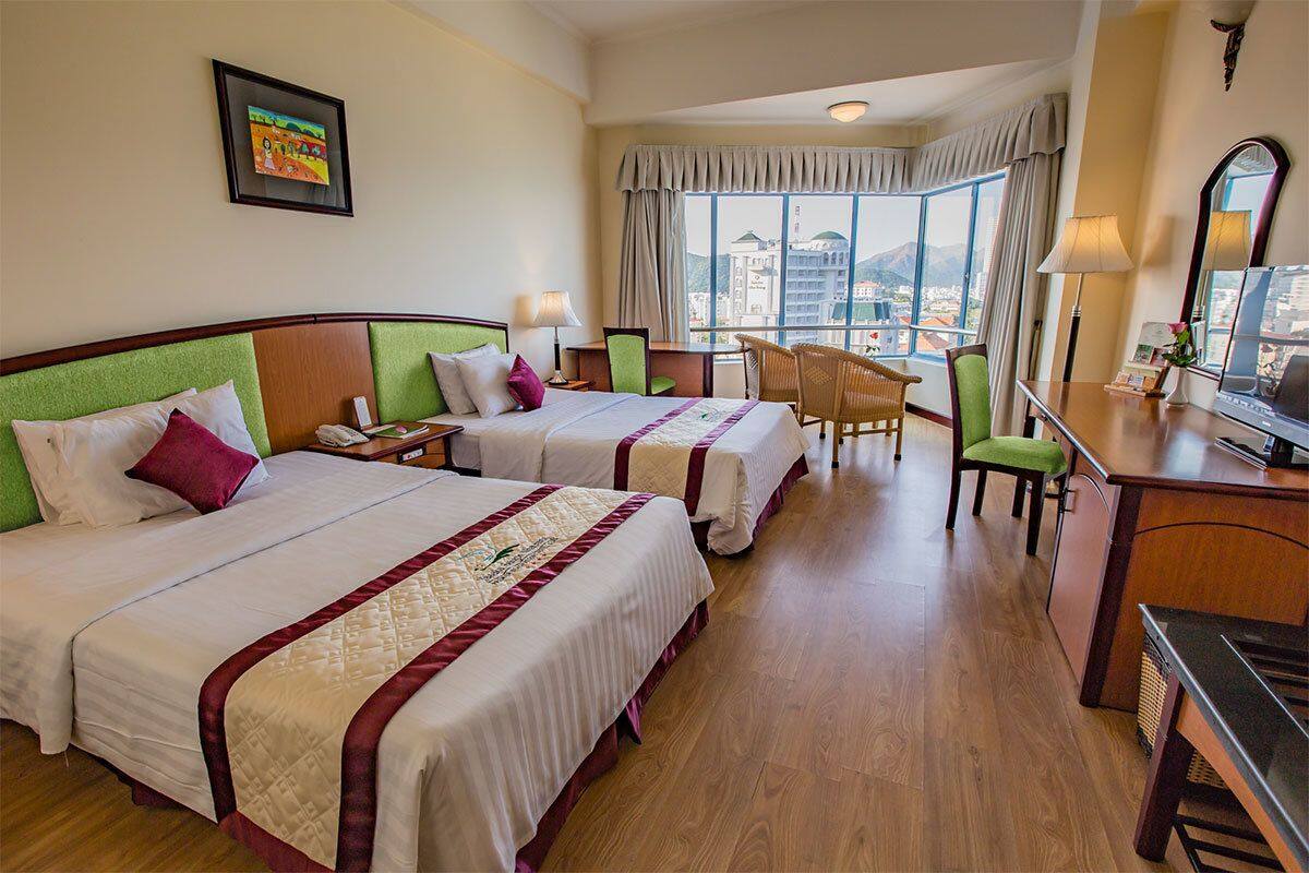 Une chambre d’hôtel avec deux lits, un bureau, une chaise et une vue sur la ville.