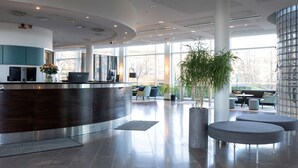 A modern reception area with a curved desk, seating, and large windows.