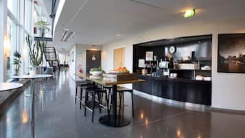 Un hall d’hôtel moderne avec un comptoir d’accueil, un espace salon et de grandes fenêtres.