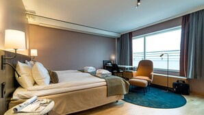 Ein Hotelzimmer mit Bett, Schreibtisch, Stuhl und einem großen Fenster.