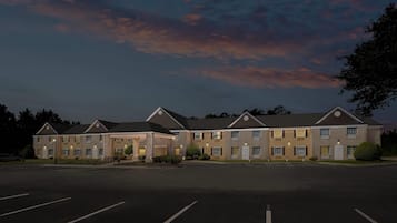 A multi-story hotel with a parking lot in front.